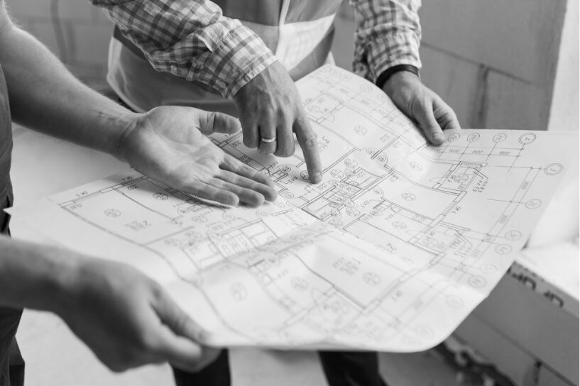 Miehet osoittamassa sormella arkkitehtipaperia